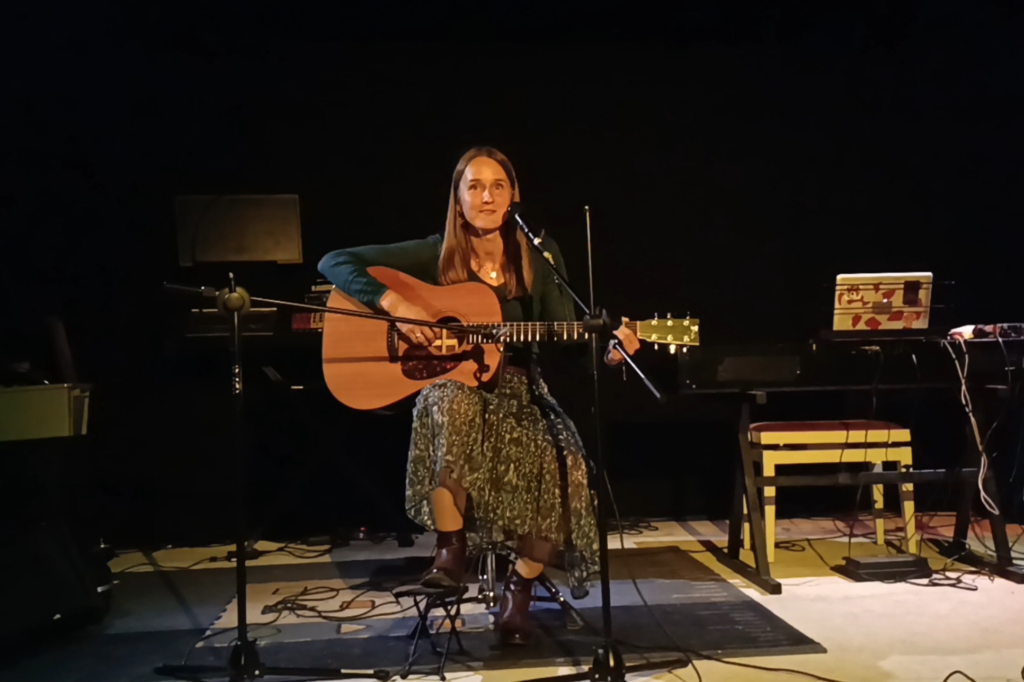 Eleve sur scène en cours de chant avec une guitare et un micro