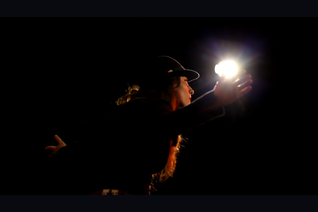 Emilie Souillot en prestation, fond noir et lumière ampoule